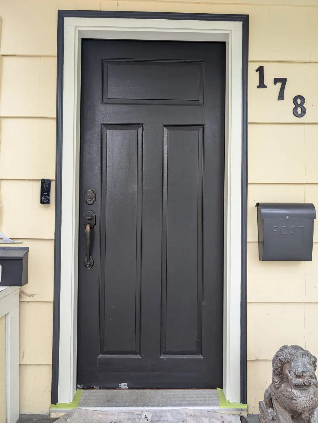 Painter inspecting freshly painted window trim and shutters on a Vancouver residential exterior.