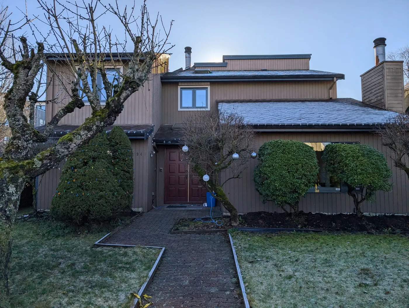 Two-story house exterior in Vancouver, BC before Renaissance Painting's exterior repaint, with original faded wood siding and a maroon front door.