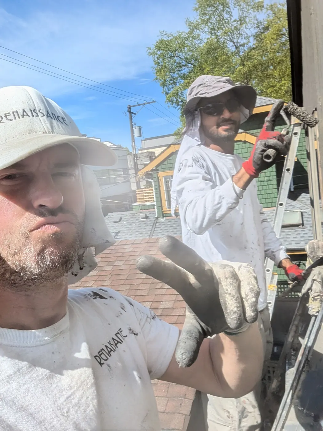 Two Renaissance Painting crew members in branded gear taking a selfie on a Vancouver, BC rooftop during an exterior job.