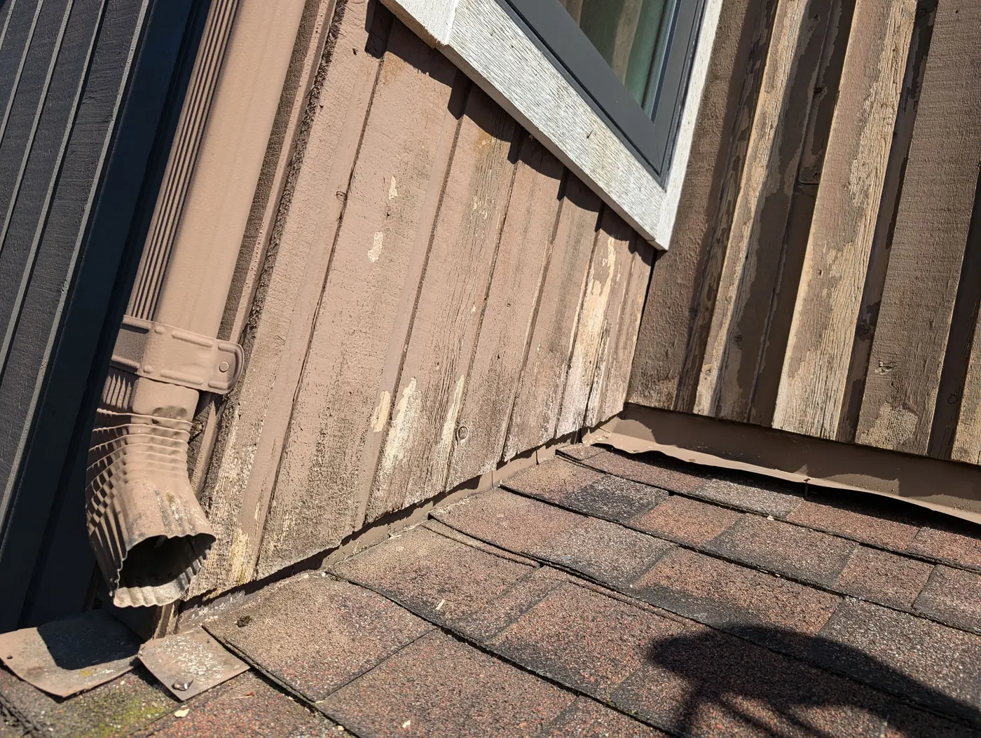 Close-up of cracked, peeling paint on wood siding and window trim at a Vancouver residence before repainting.