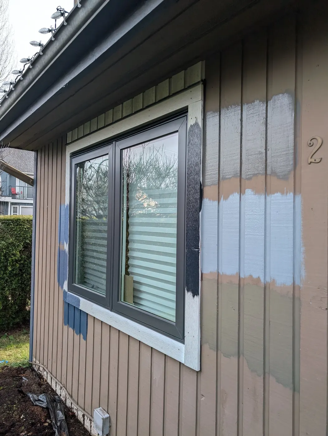 Sample swatches of blue and taupe exterior paint tested on cedar siding at a Vancouver, BC residence.