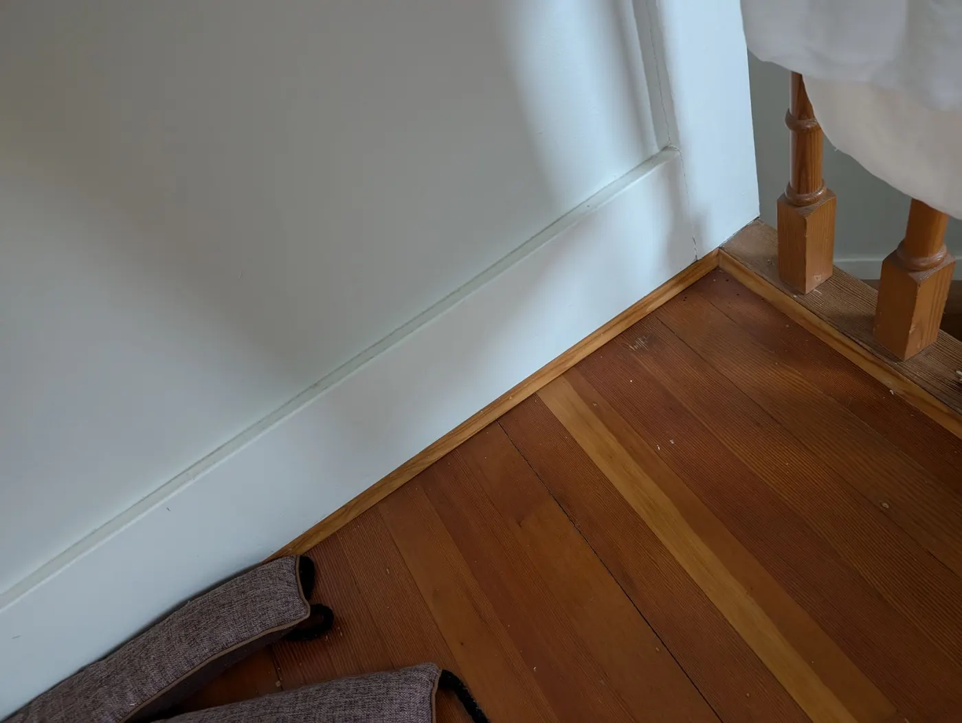 Crisp white baseboard trim freshly painted against original wood flooring in a Vancouver home