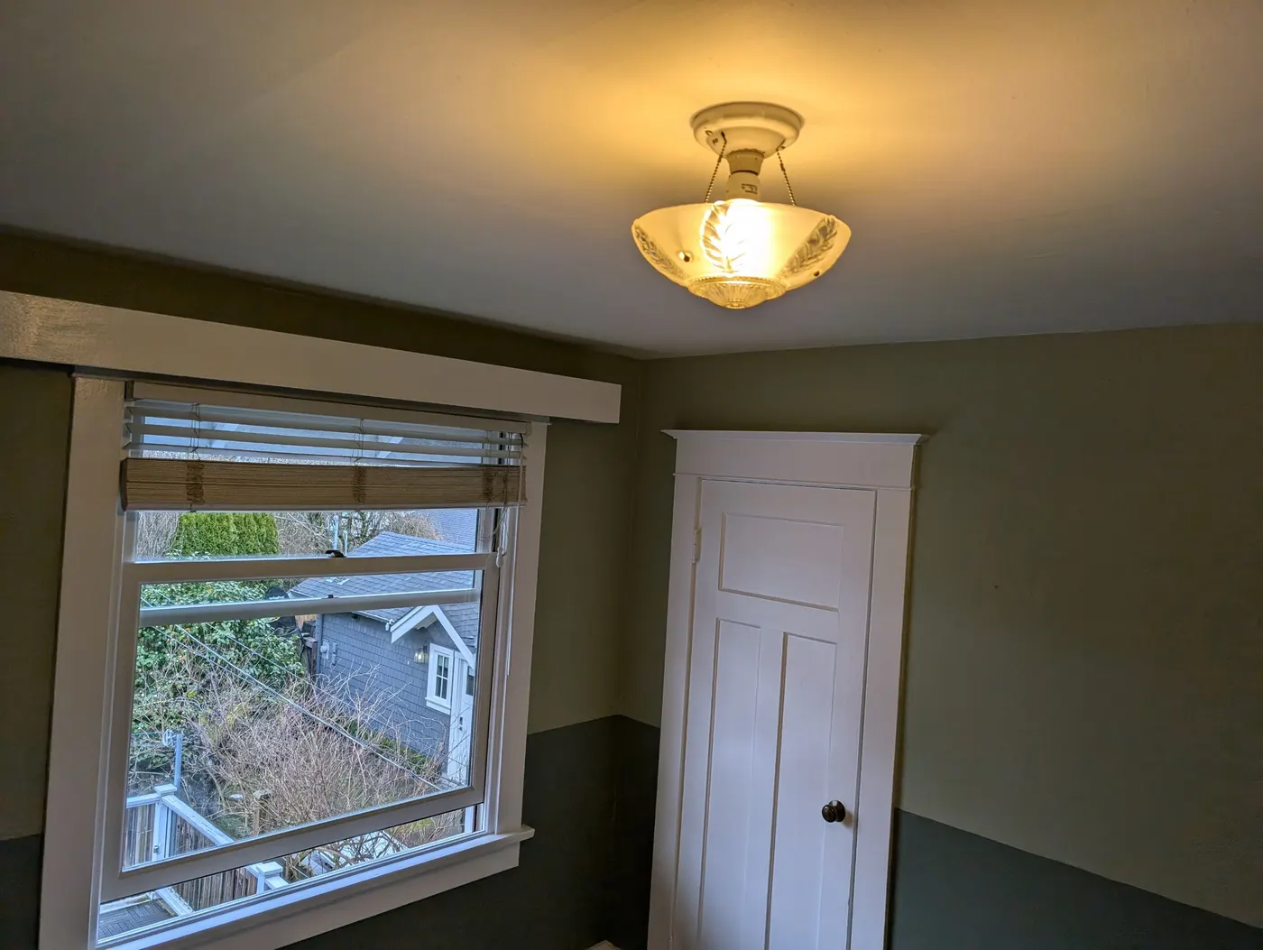 Finished two-tone sage green and charcoal bedroom with vintage light fixture in a Vancouver character home