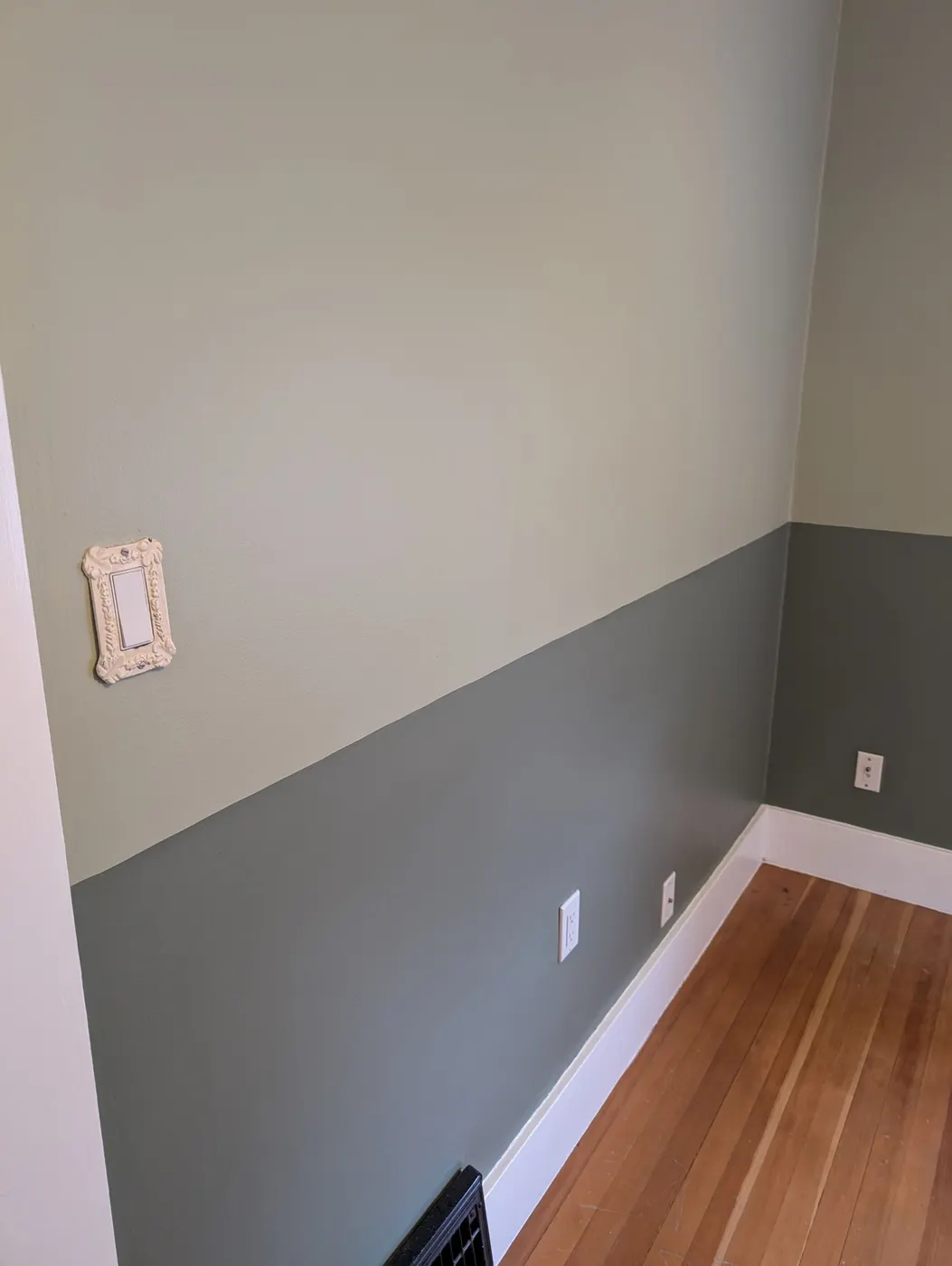Crisp two-tone paint line along a bedroom corner with vintage outlet cover in a Vancouver home