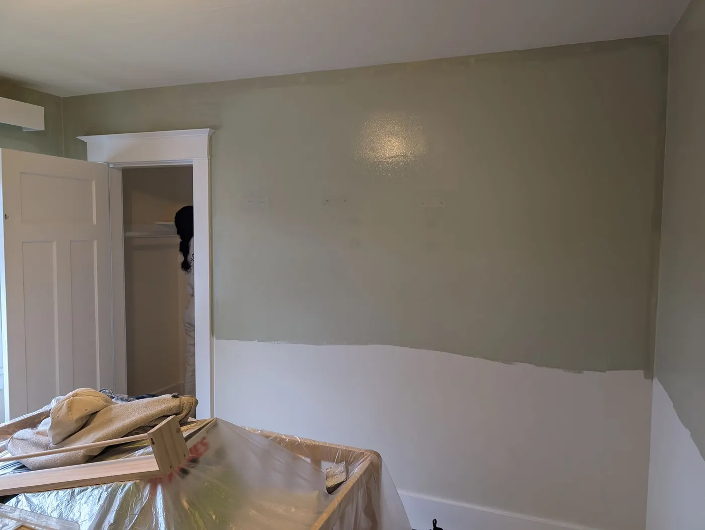 Painter applying sage green paint above a white two-tone wall in a Vancouver bedroom renovation