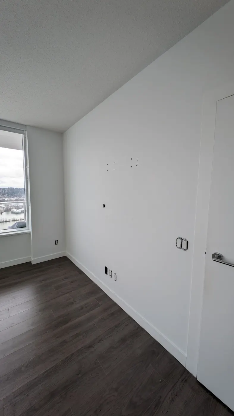 White baseboard and trim carpentry along a bedroom wall in a Vancouver, BC condo renovation.