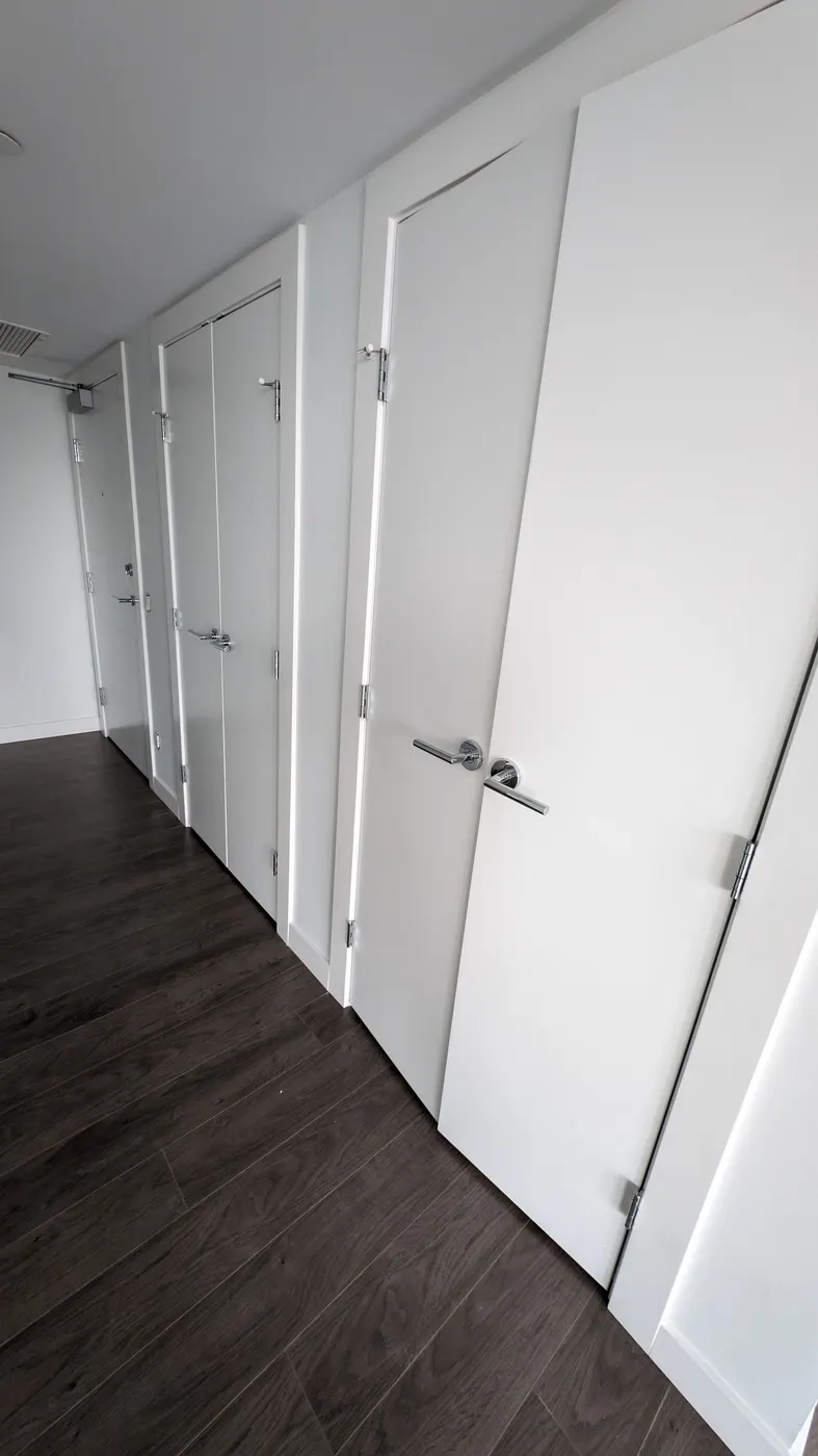White door casings and baseboard trim along a hallway in a Vancouver, BC condo renovation.