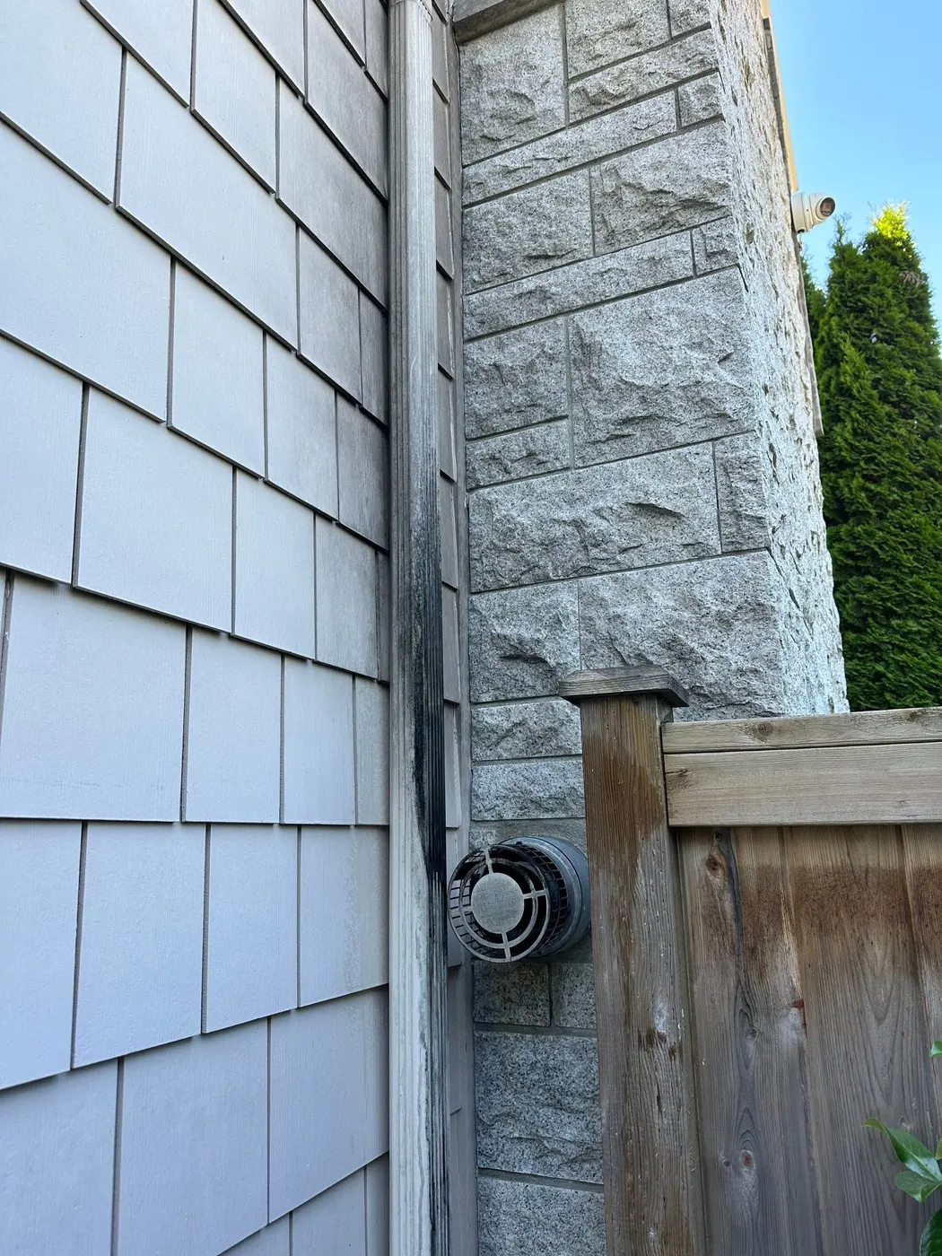 Painted grey cedar shingle siding meeting a stacked stone corner on a house exterior in Beechwood, Vancouver, BC.