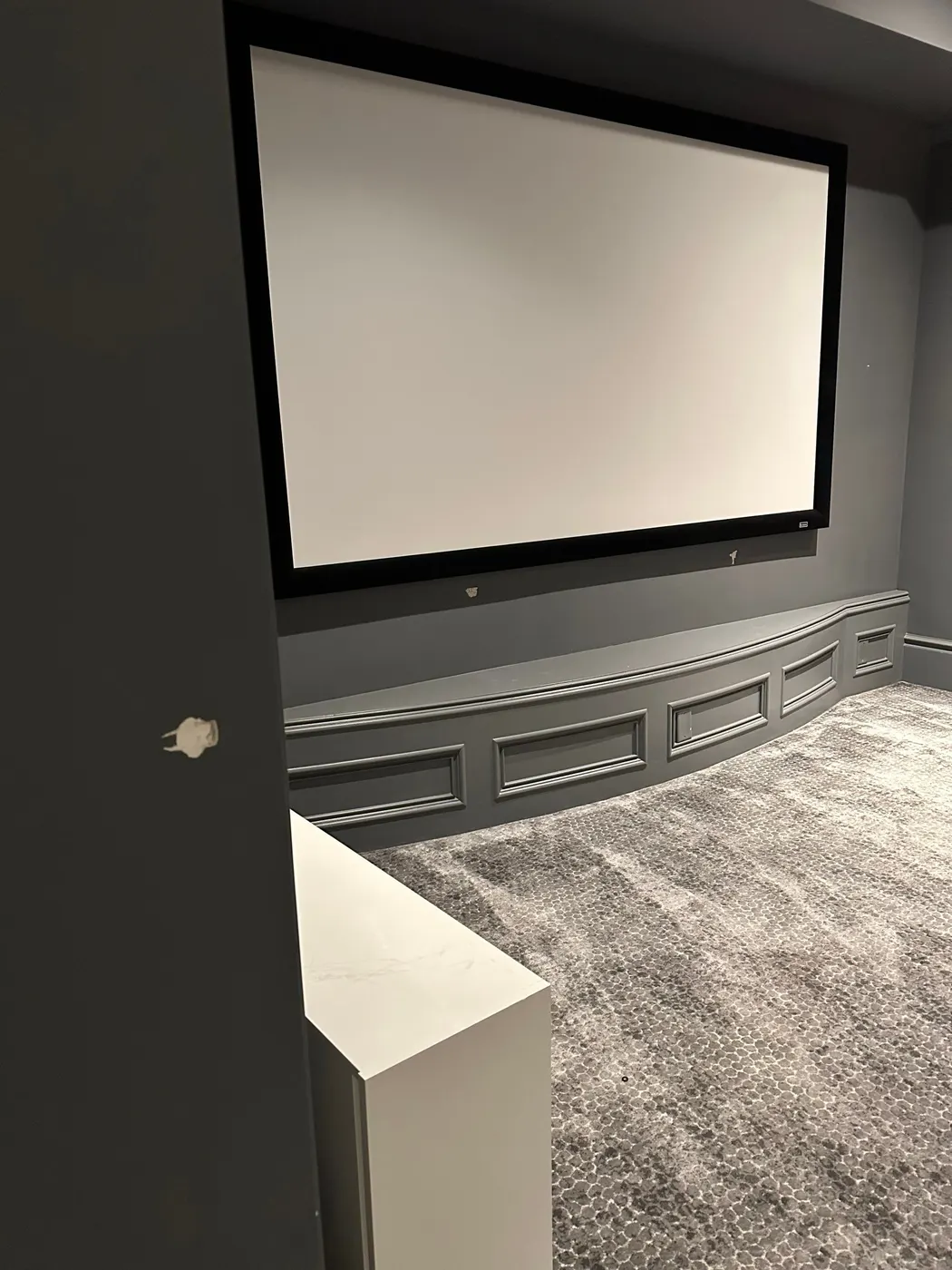 Freshly painted grey accent wall with a built-in projector screen in a Vancouver, BC home theatre room, painted by Renaissance Painting.