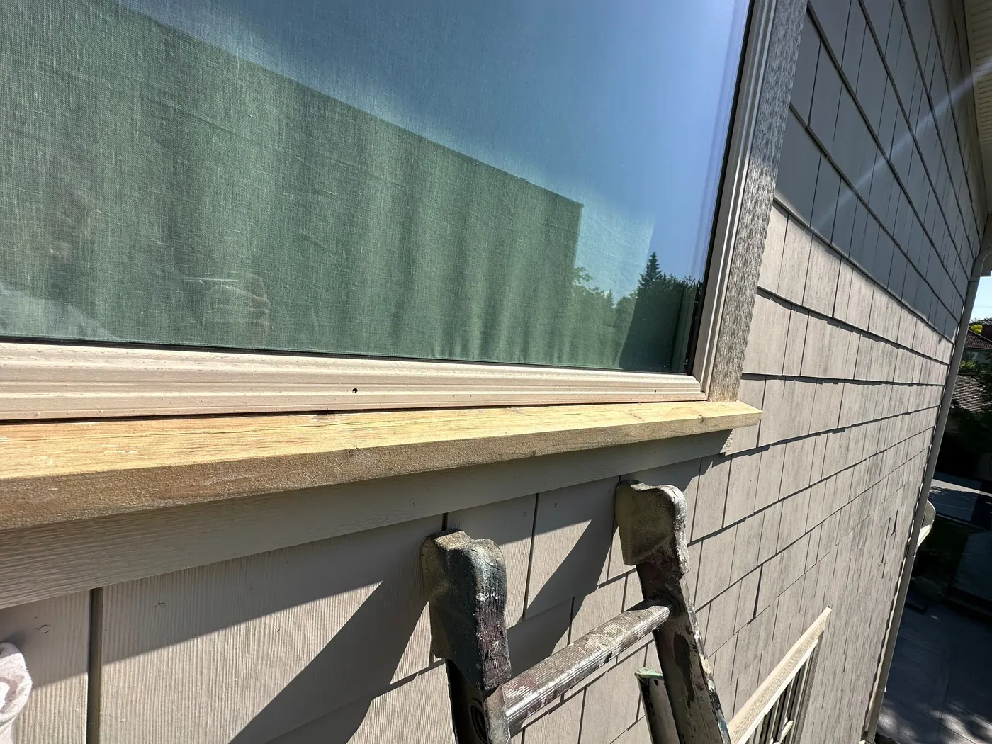 Carpenter's ladder set beside a newly installed wood window sill on a home exterior in Beechwood, Vancouver, BC.