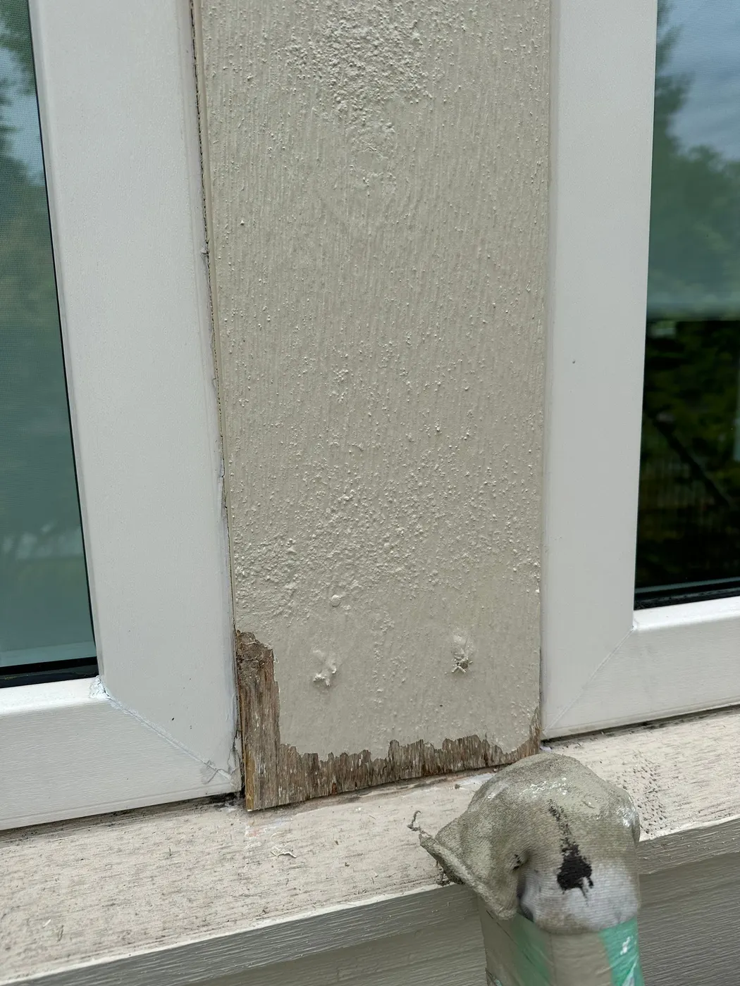 Carpenter sanding a weathered wood window sill before repair on a house exterior in Beechwood, Vancouver, BC.