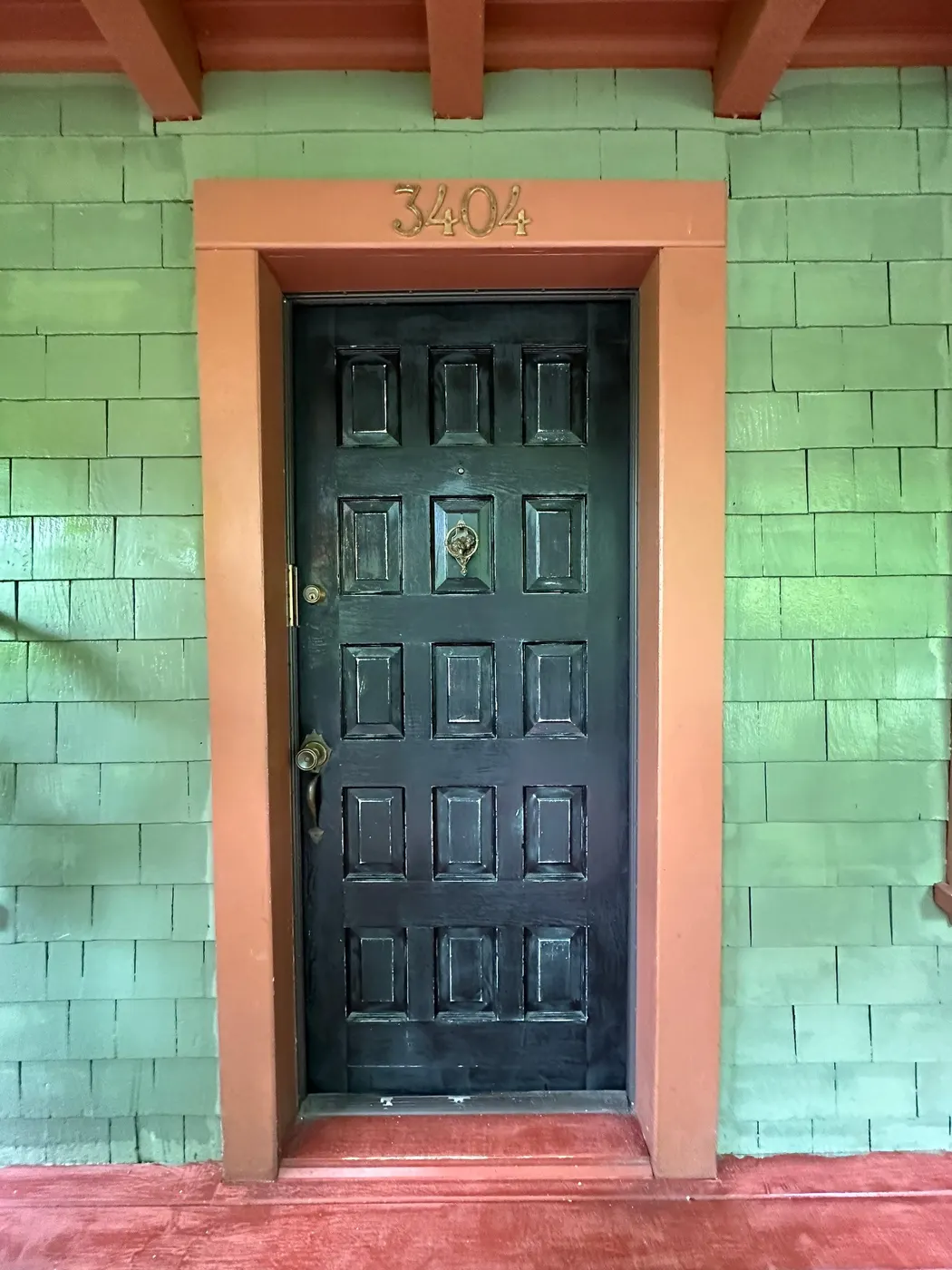 Glossy black paneled front entry door with brass hardware on a Vancouver character home