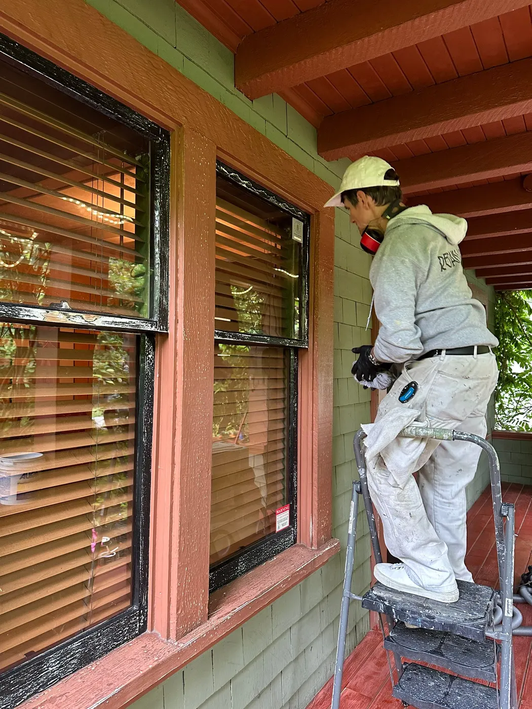 Renaissance Painting crew member on a step ladder painting exterior window trim on a Vancouver, BC home