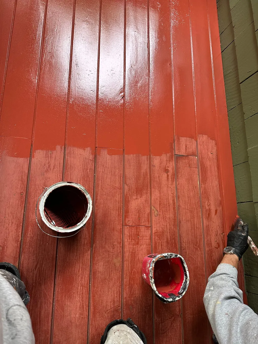 Freshly painted red porch deck boards mid-application during a Vancouver exterior painting project