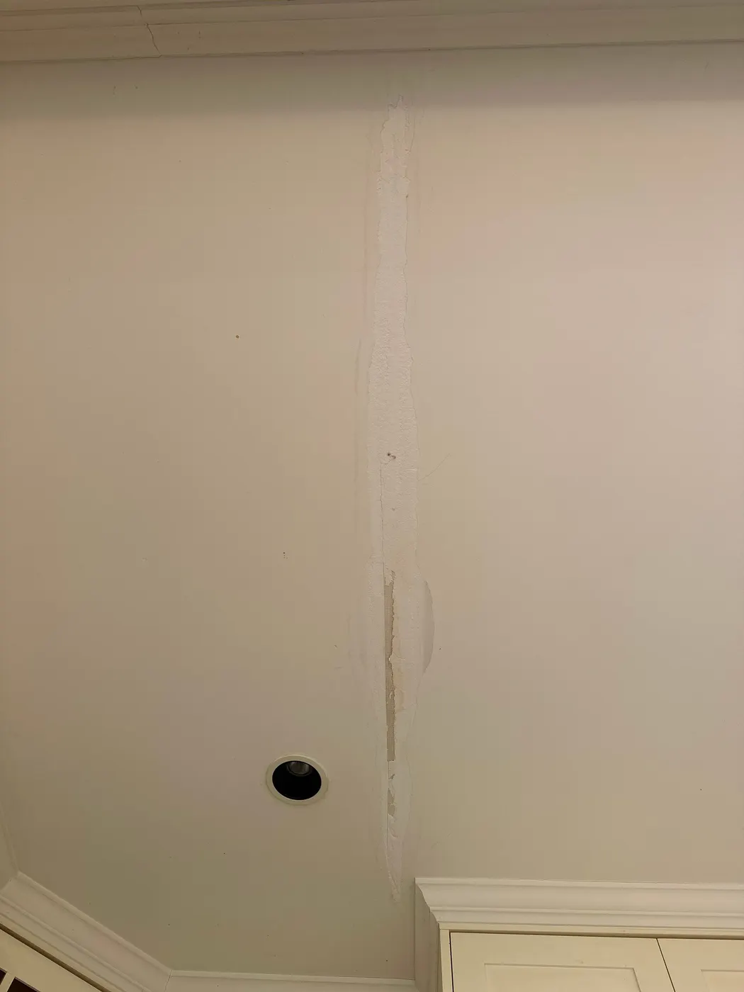 Vertical ceiling-to-wall crack repair with mesh tape in a Vancouver home, prepped by Renaissance Painting.
