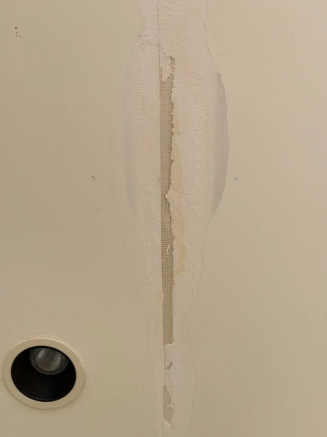 Close-up of a drywall crack repaired with fiberglass mesh tape and compound in a Vancouver interior painting job.