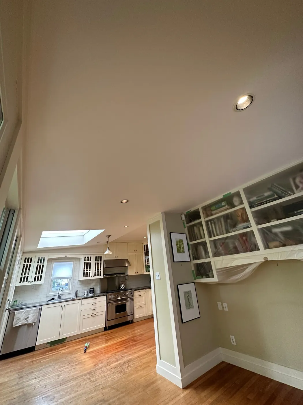 Open-concept kitchen and dining area in a Vancouver home prepped for interior painting with cabinets covered.
