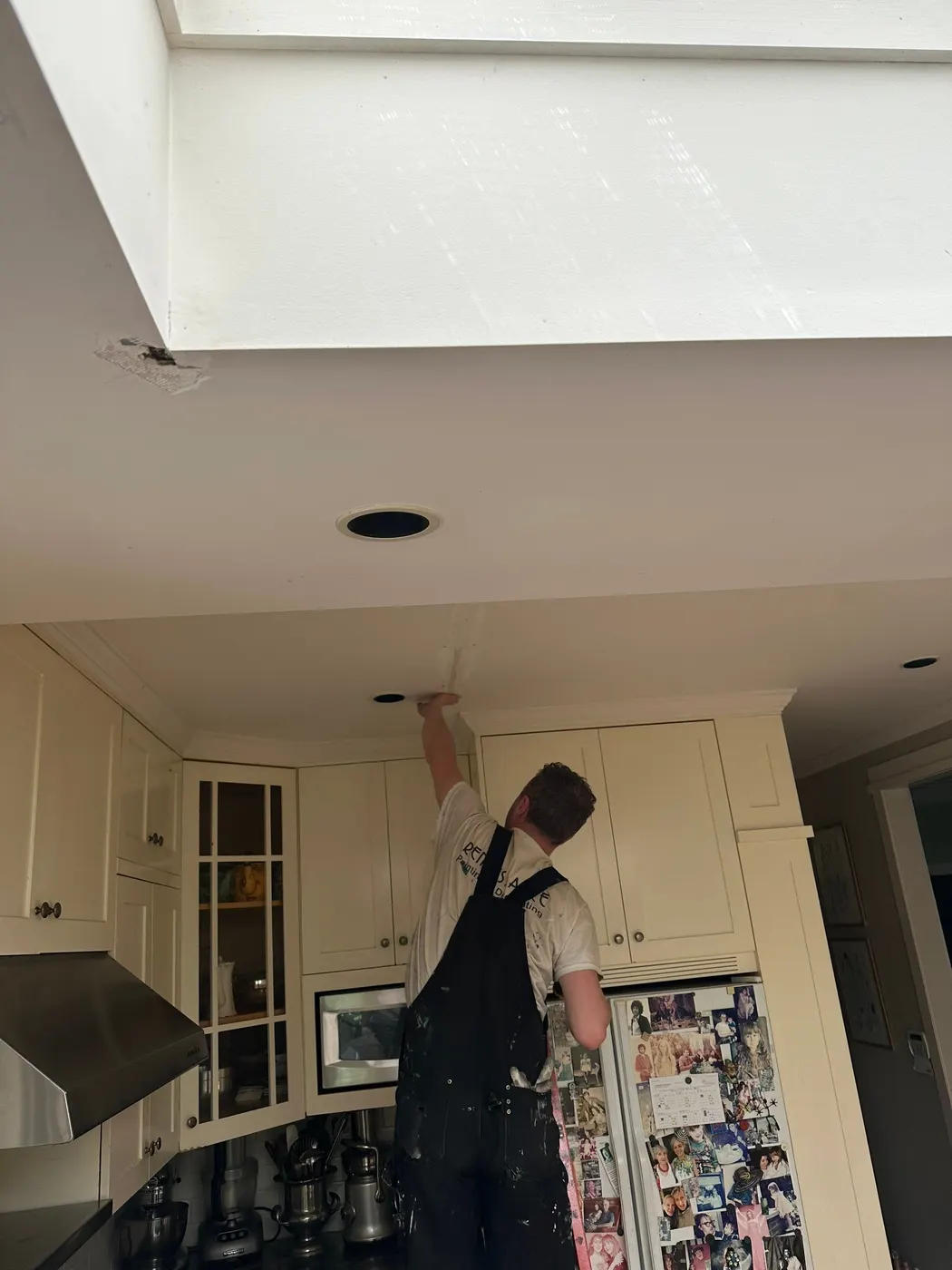Renaissance Painting crew member repairing a ceiling crack above kitchen cabinets in a Vancouver home.