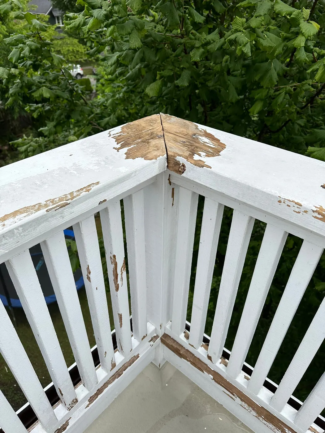 Close-up of peeling paint and exposed wood on a deck corner post in Vancouver, BC before repair