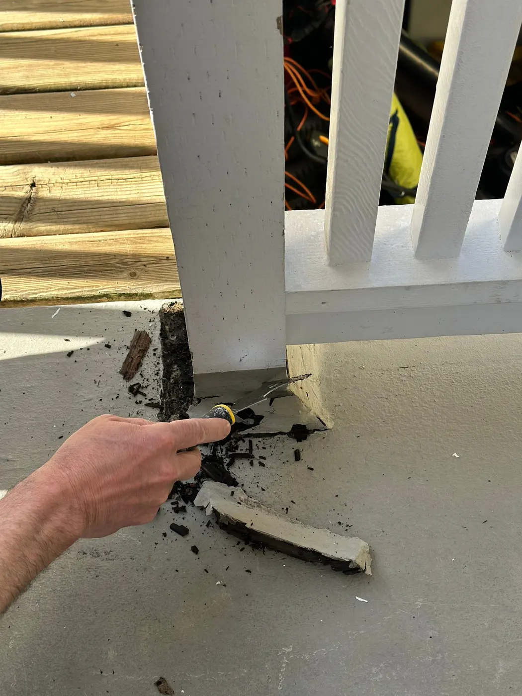 Renaissance Painting carpenter scraping out rotted wood at a deck post base in Vancouver, BC