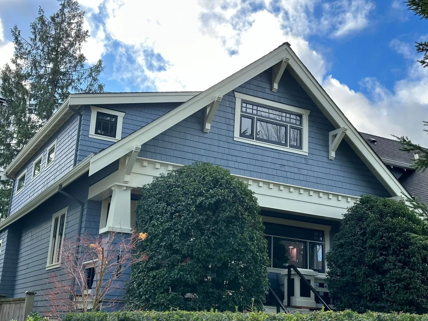 Blue Craftsman house exterior with white gable trim and covered porch, painted by Renaissance Painting in Vancouver, BC.