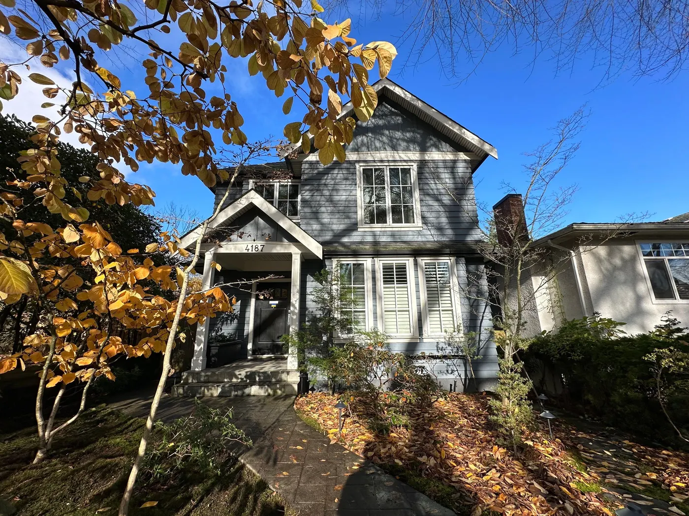 Blue-gray two-story Craftsman house exterior with a covered entry, painted by Renaissance Painting in Vancouver, BC.