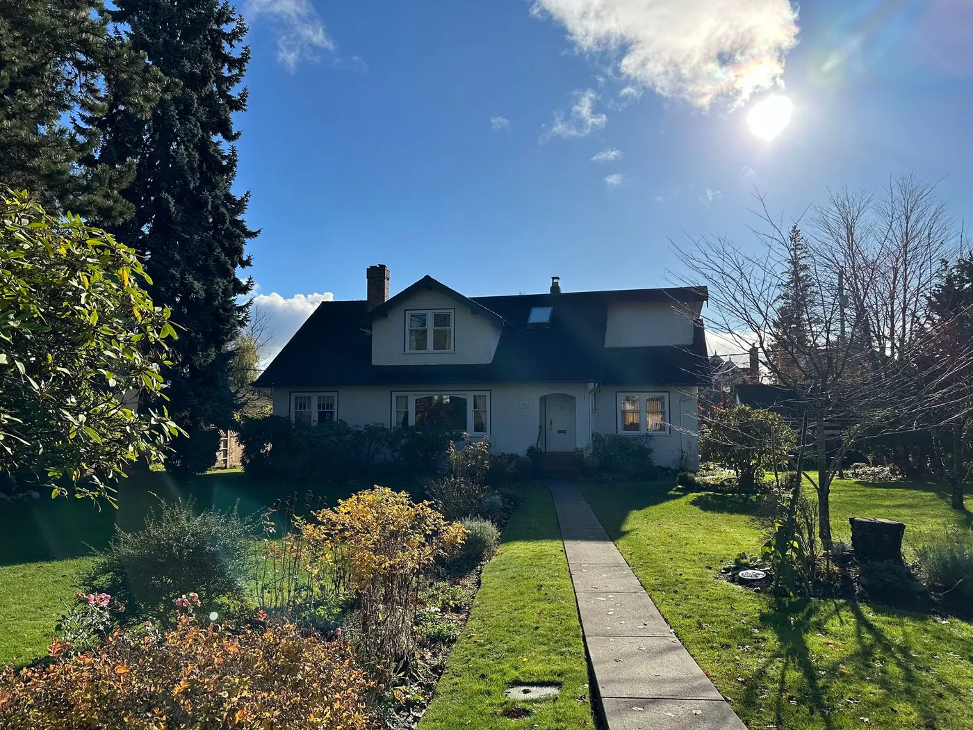 Cream stucco cottage exterior with a dark shingled roof, painted by Renaissance Painting in Vancouver, BC.