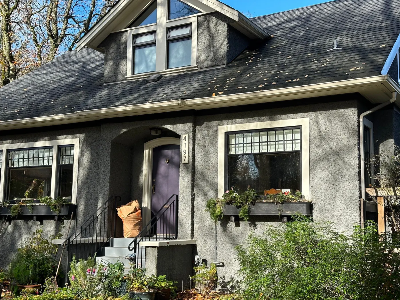 Gray stucco cottage exterior with a purple front door, painted by Renaissance Painting in Vancouver, BC.