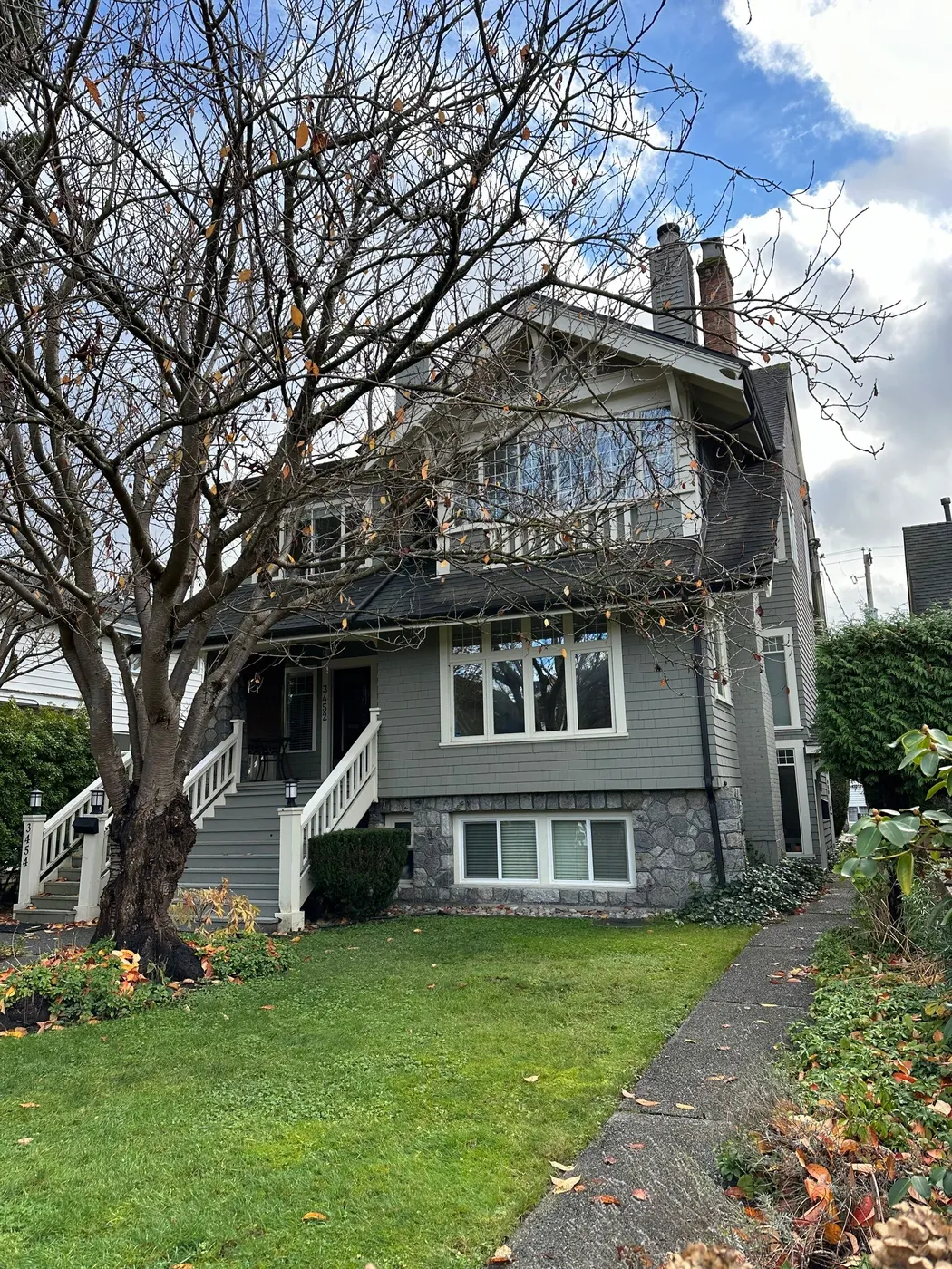 Sage green Craftsman house exterior with white trim and stone foundation, painted by Renaissance Painting in Vancouver, BC.