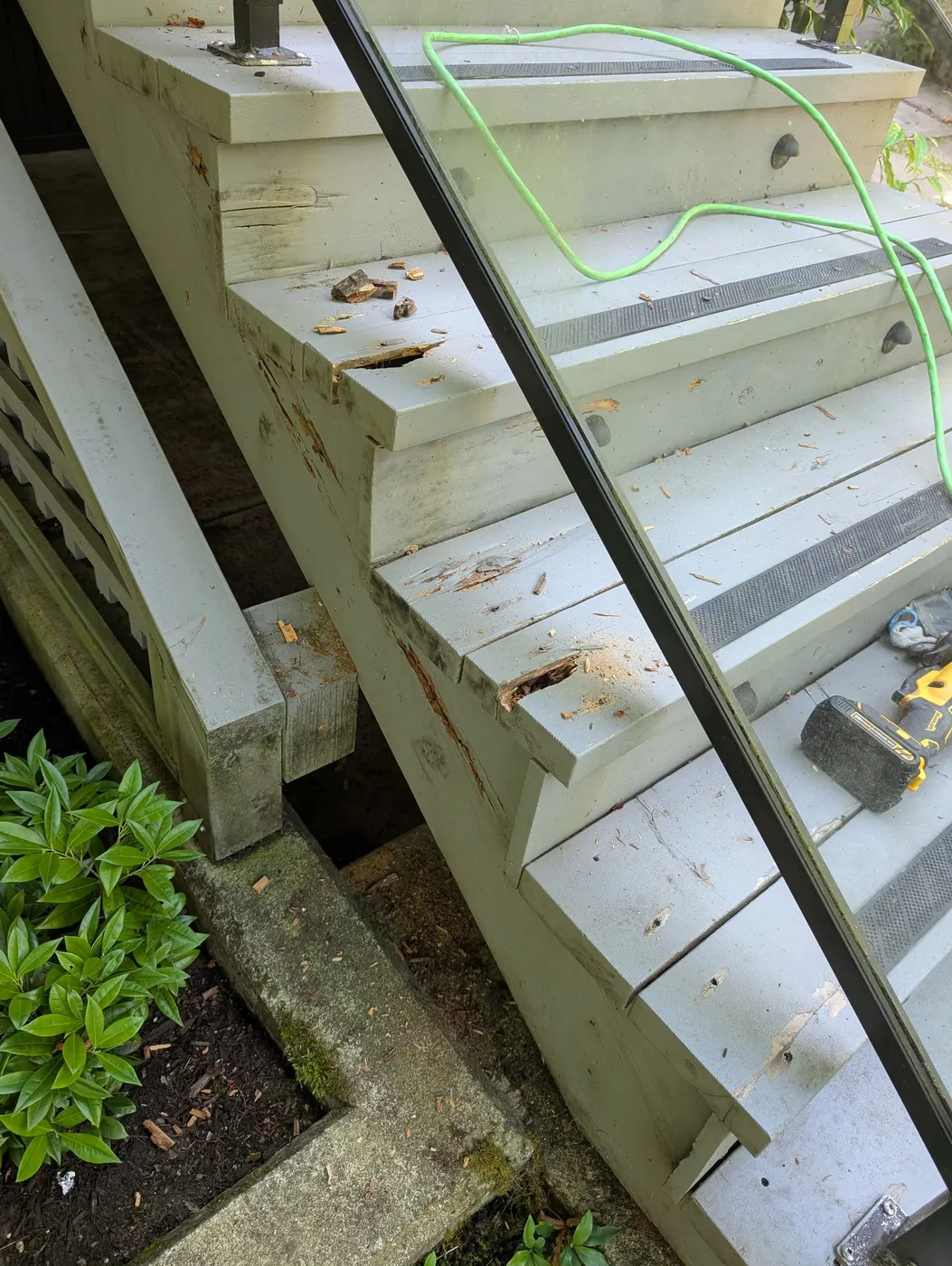 Close-up of damaged exterior wood deck stair treads with tools during carpentry repair in Vancouver