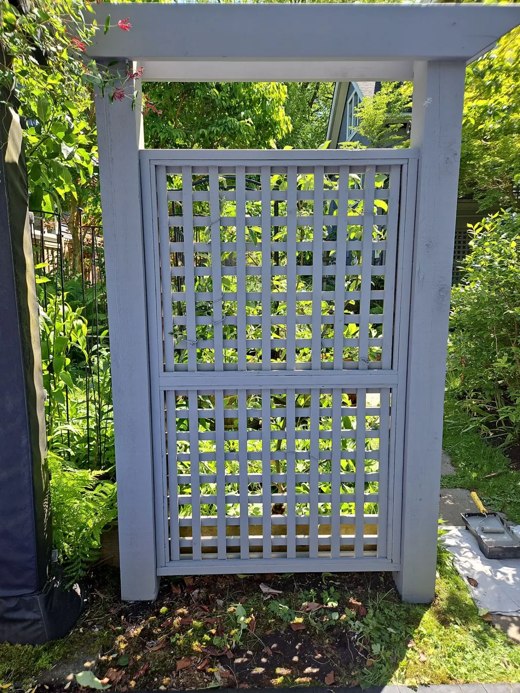 Finished grey-painted wood lattice garden gate and arbor in a Vancouver backyard