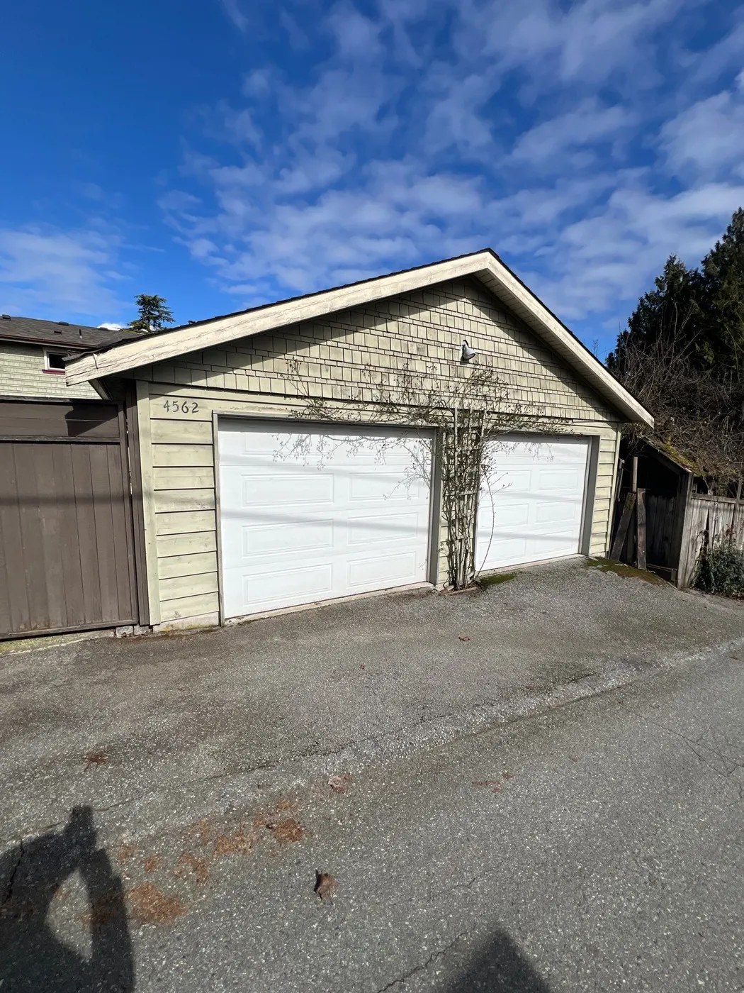 Detached two-car garage with cream shingle siding at a Vancouver, BC residence before exterior painting