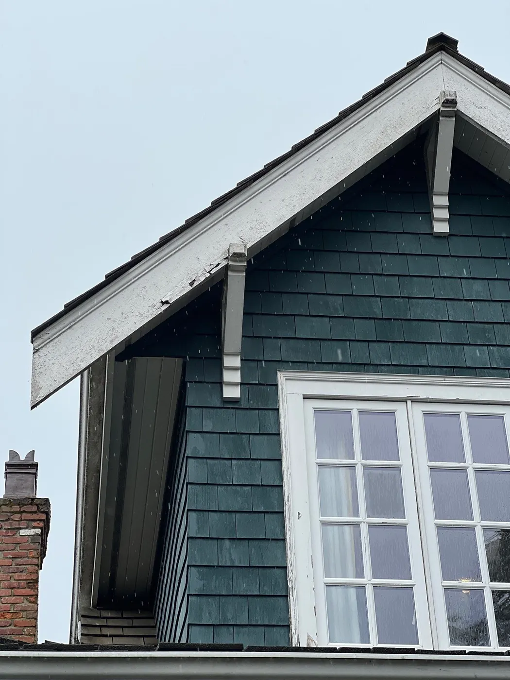 Peeling paint on a dormer gable eave and green cedar shingle siding on a Vancouver, BC character home before exterior repainting