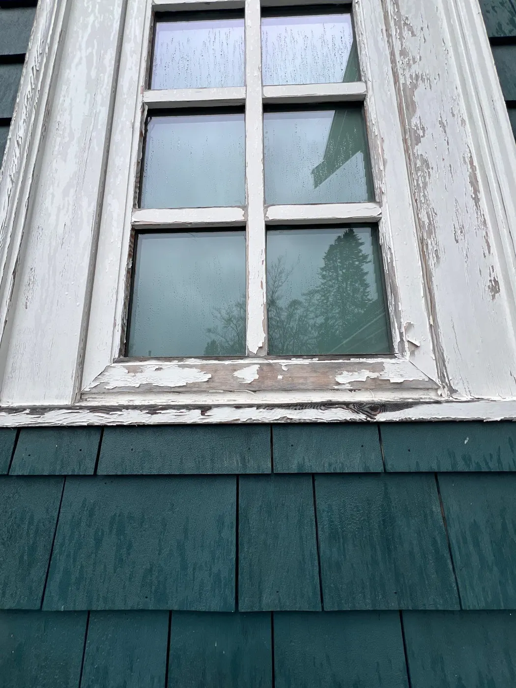 Close-up of cracked and peeling white paint on a wood window frame at a Vancouver, BC home needing exterior painting