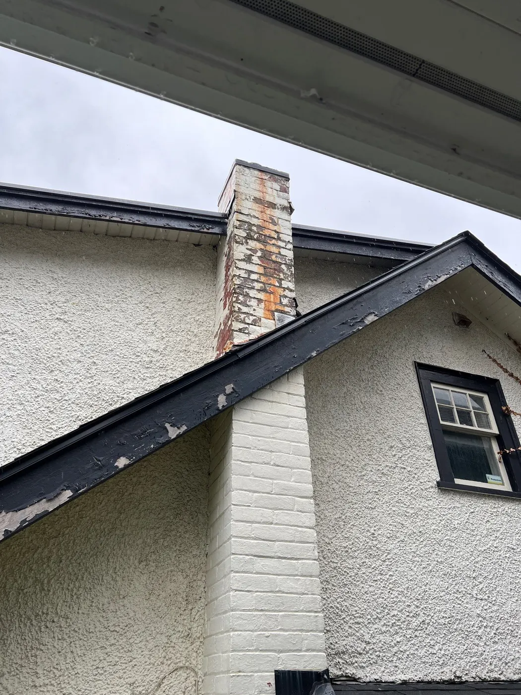 Brick chimney and stucco gable prepped for exterior painting on a Vancouver, BC rental property.