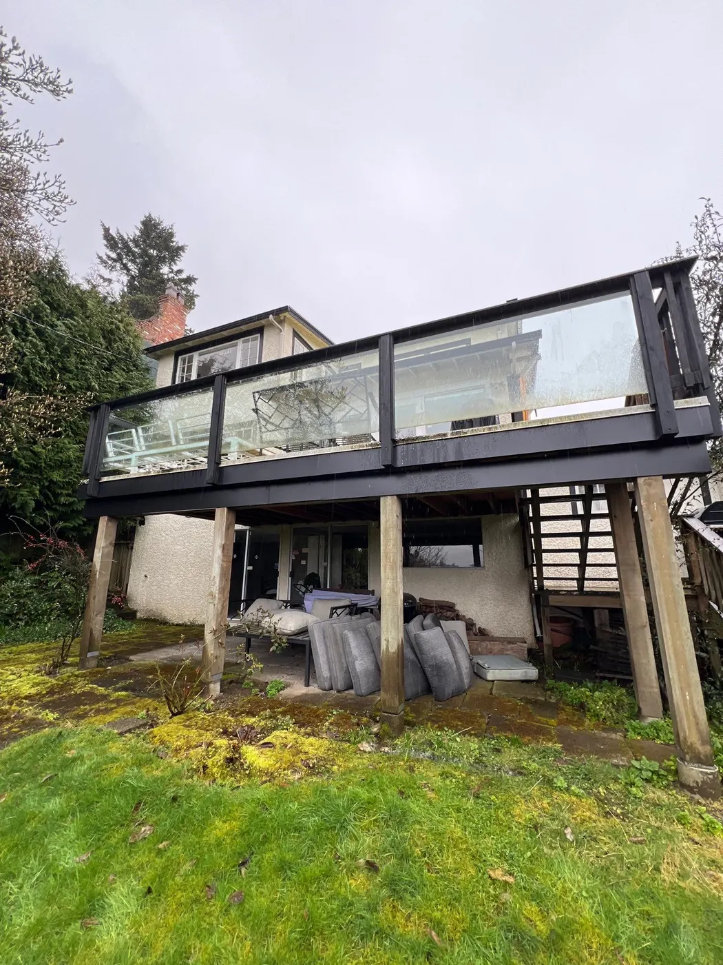 Rear exterior of a two-storey Vancouver rental home with elevated deck, ready for a full repaint.