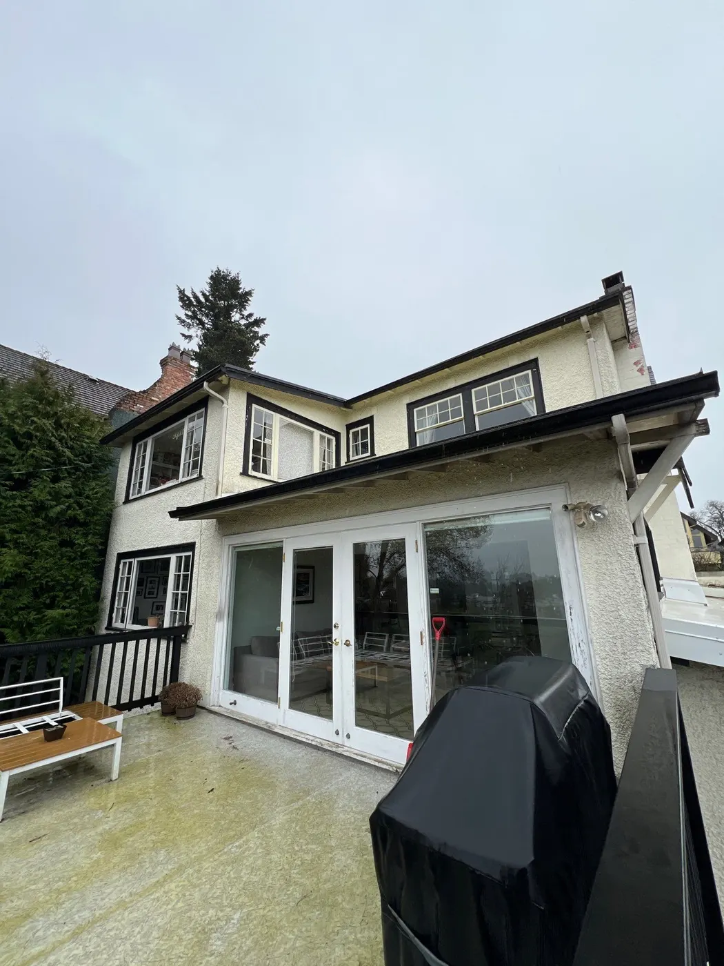 Two-storey stucco house with black-trimmed windows and patio doors, exterior painting project in Vancouver, BC.