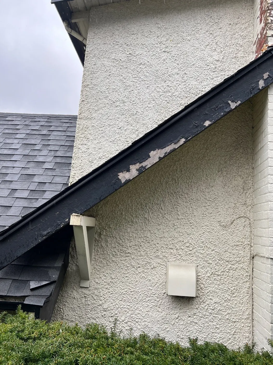 Peeling black fascia and gable trim on a stucco house exterior, Vancouver BC repaint project.