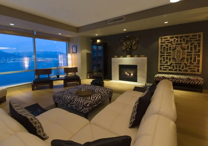 A well-designed room with a high ceiling, contrast between the furniture and light fixtures, and an abundance of natural light.