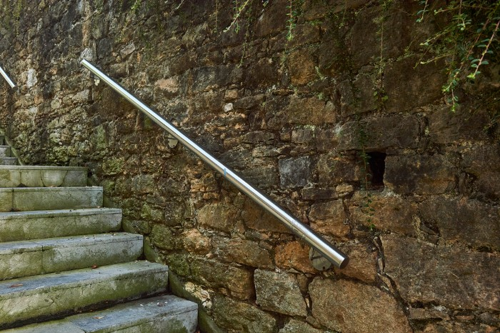 Stone wall with modern stainless steel handrails.