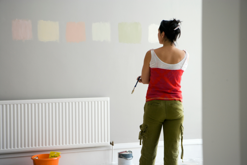 Woman testing paint options on wall.