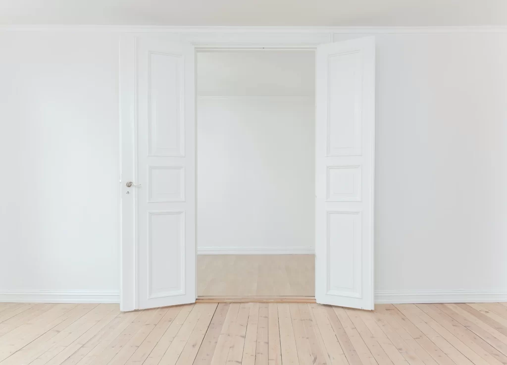 An opened white door in a white room.