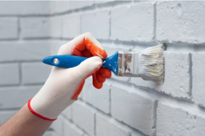 A painter is painting a white brick wall