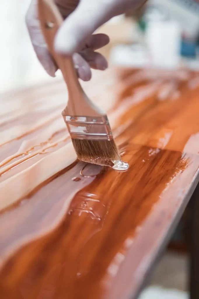 A painter is putting stain on a wooden surface.