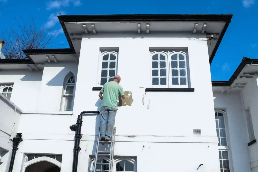 A painter is painting stucco in a white colour.