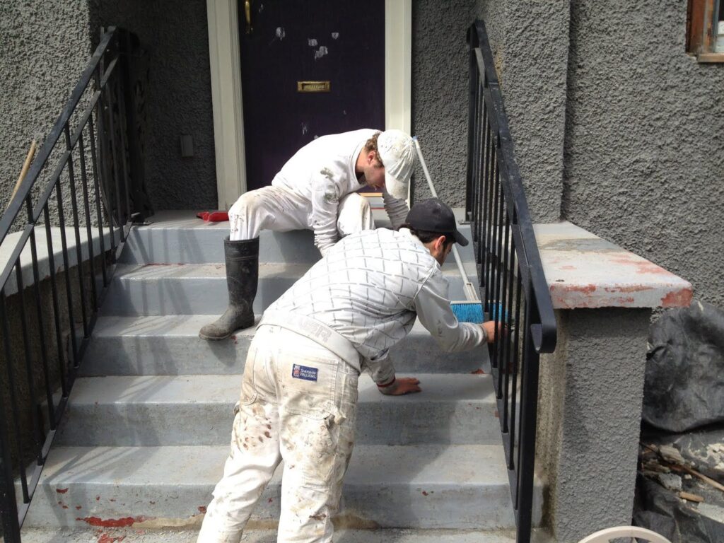 2 painters are painting exterior front stairs and railings.