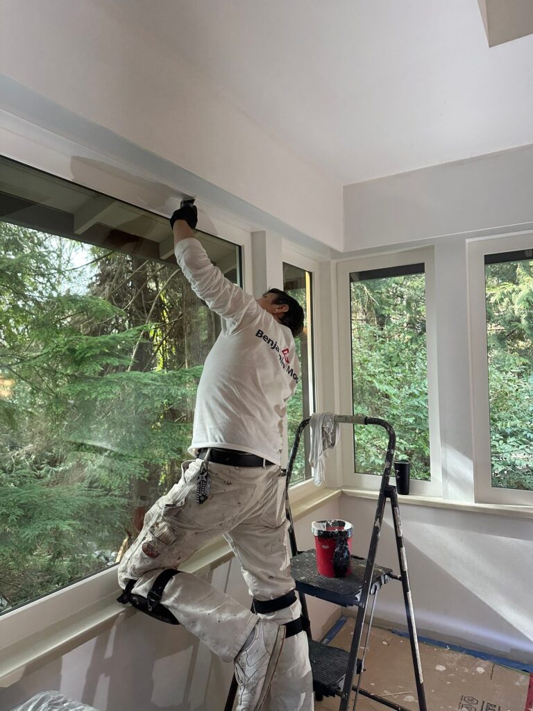 Painter is painting drywall around the window with a brush