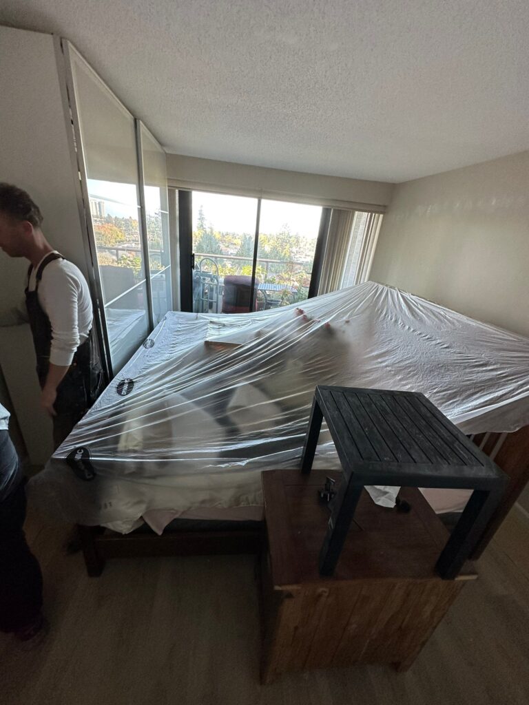 Wrapping the furniture and preparing the workspace before painting.