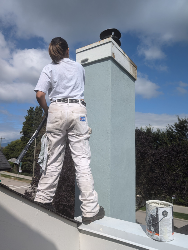 Painter is painting a metal chimney rain cap.