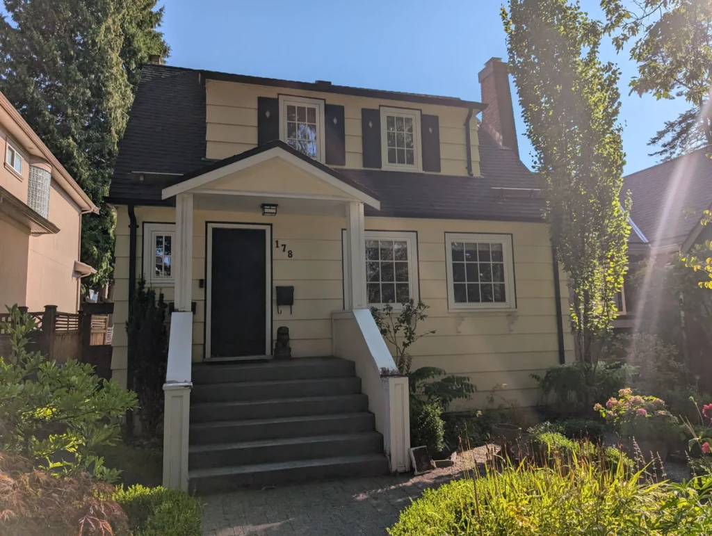 Curb appeal vie on a cream colour house in Vancouver with recently reinstalled door.